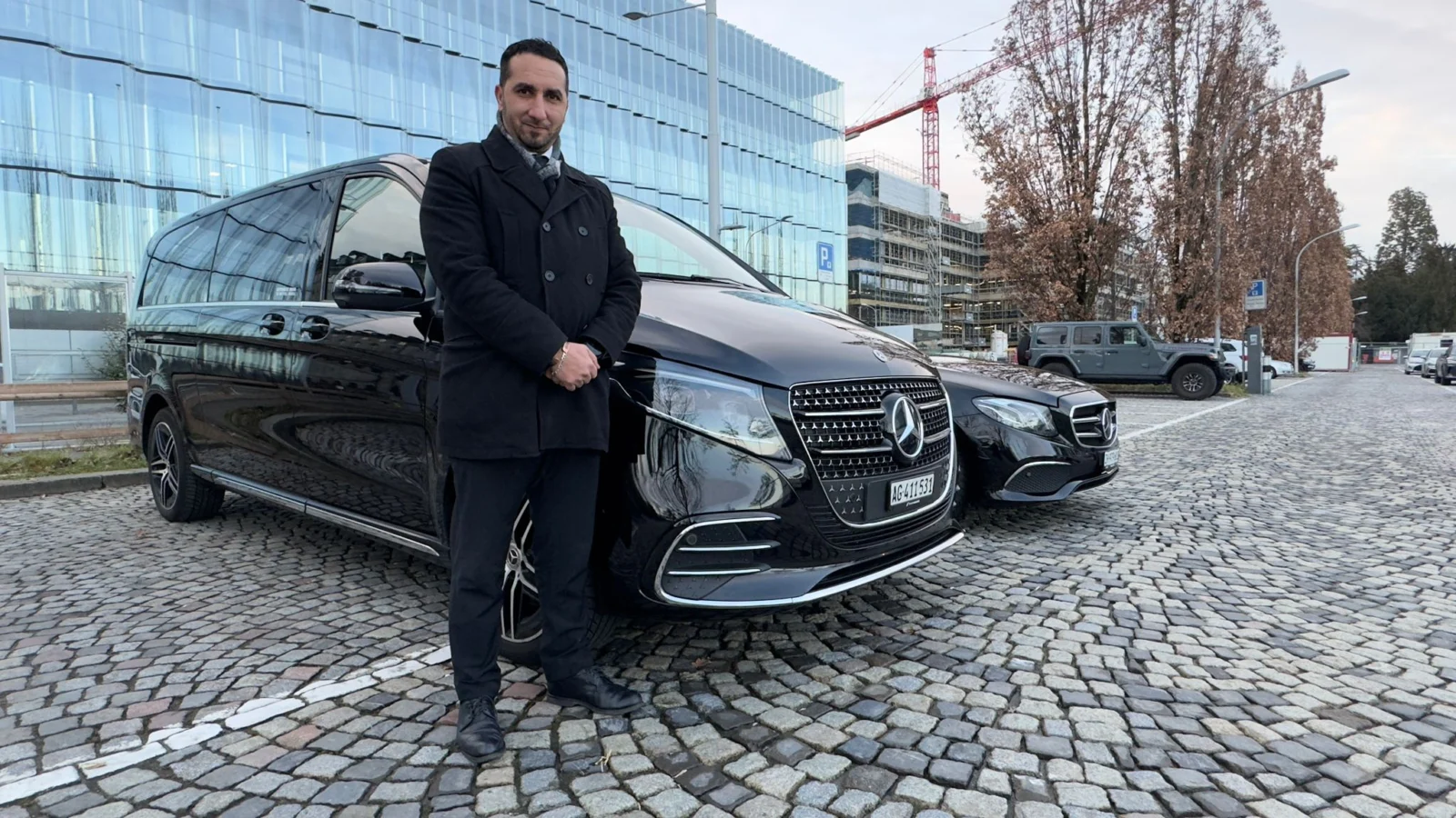 Ali standing beside a black Mercedes chauffeur van