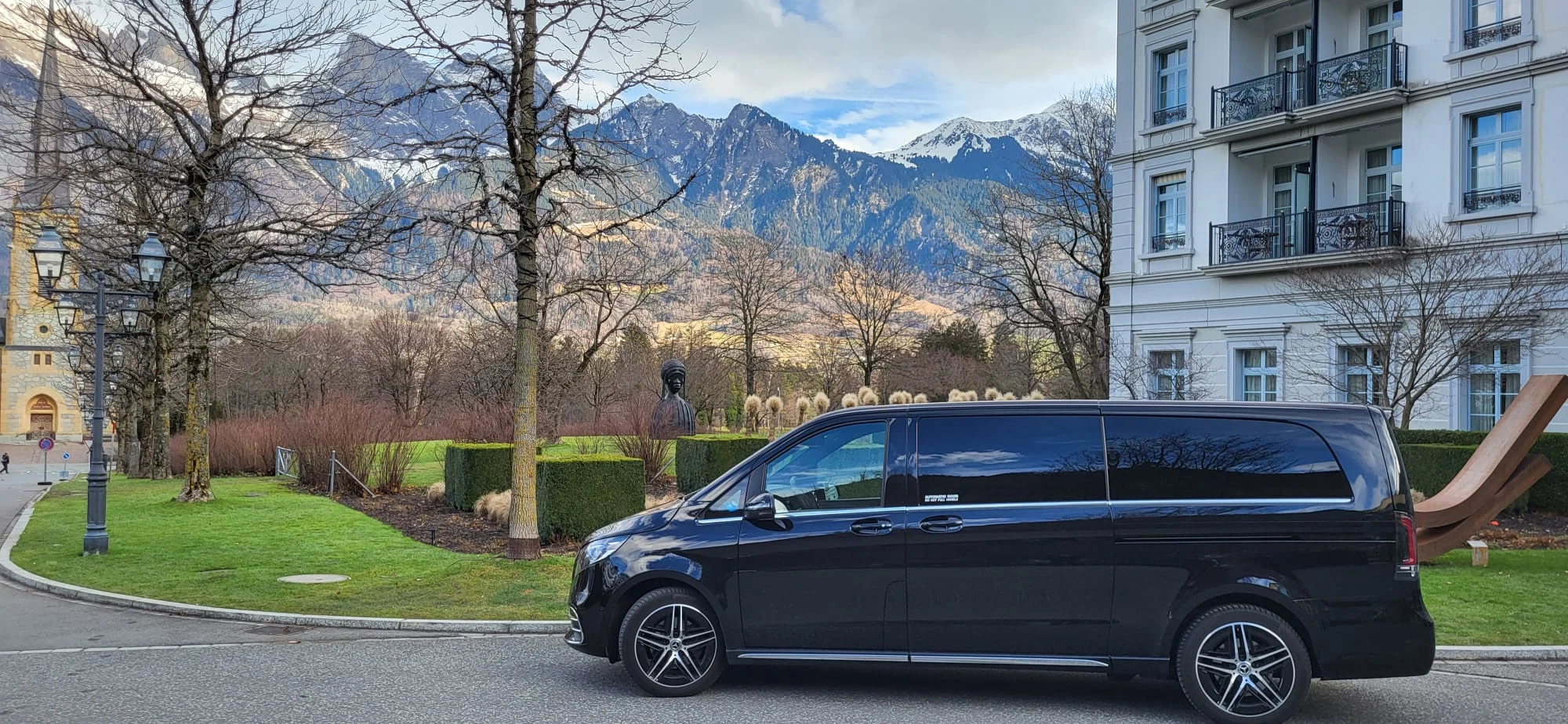 Black Mercedes chauffeur van with Swiss alpine mountains in the background